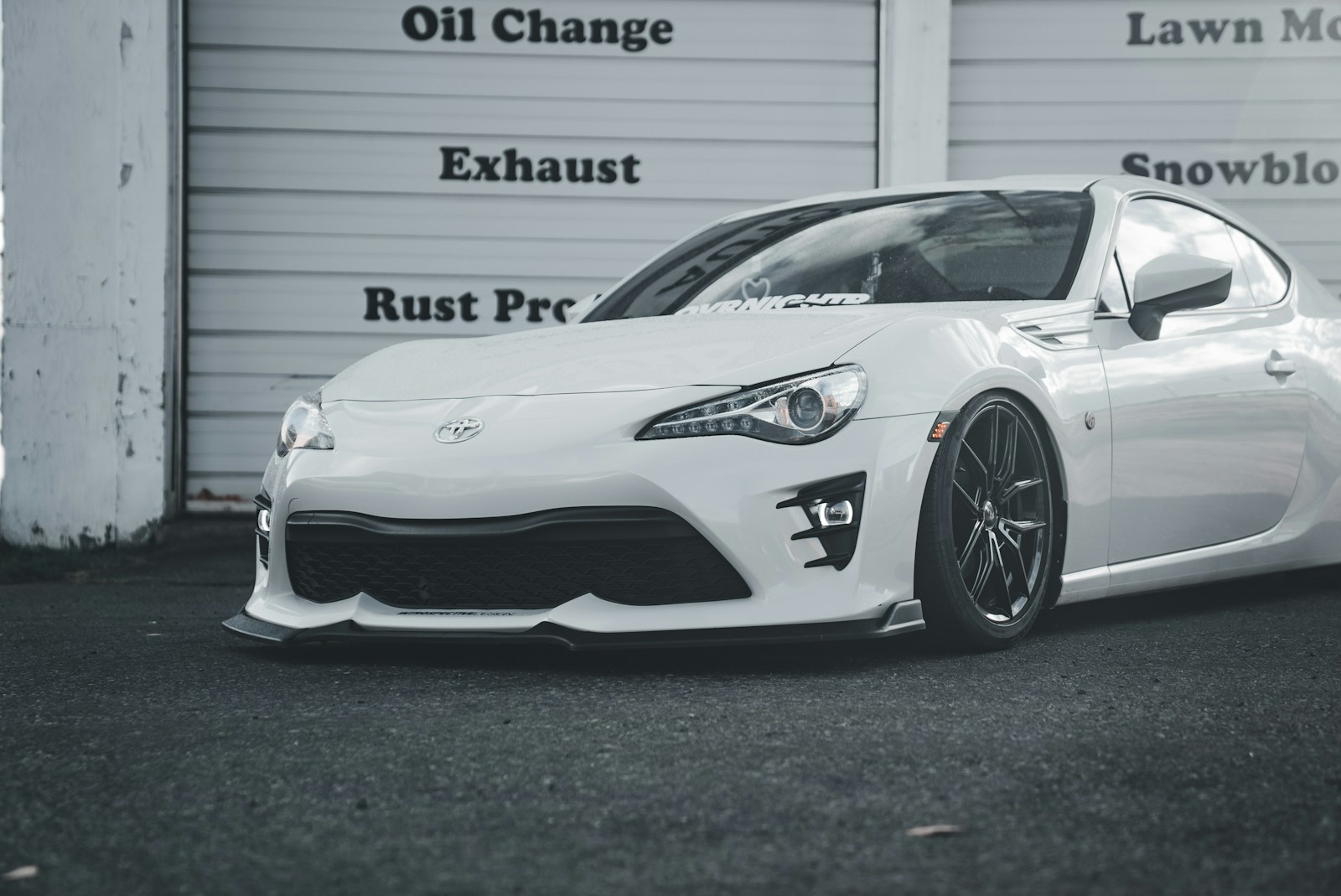 A white sports car parked in front of a garage